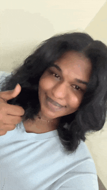 a woman giving a thumbs up while wearing a white shirt