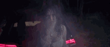 a woman in a white dress is sitting in the back of a car at night .