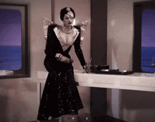 a woman in a black and silver dress is sitting at a counter
