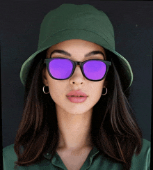 a woman wearing a green hat and purple sunglasses looks at the camera