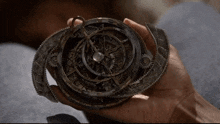 a person is holding a mechanical device in their hand that looks like a compass
