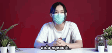 a woman wearing a face mask is sitting at a table with plants