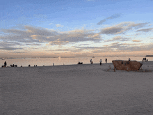 a group of people are gathered on a beach with a large rock in the middle