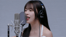 a woman wearing a pair of sony headphones sings into a microphone