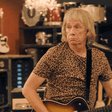 a man wearing a leopard print shirt is playing a guitar