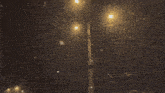 a street light is lit up at night while snow is falling .