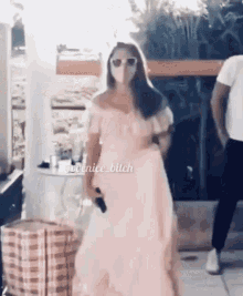 a woman in a pink dress is wearing a mask and sunglasses while holding a gun .