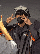a person wearing a black mask and a black jacket with a chinese symbol on the front