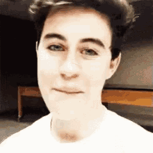 a close up of a man 's face with a white shirt on .