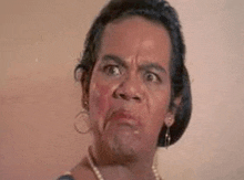a woman wearing a pearl necklace and earrings is making an angry face .