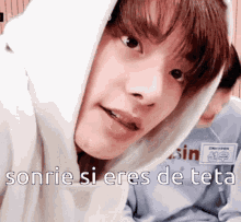 a close up of a person wearing a white hoodie with the words sonrie si eres de teto