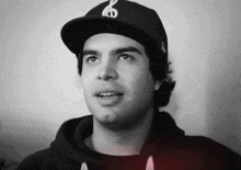 a young man wearing a black hat with a white letter s on it