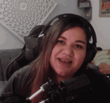 a woman wearing headphones and a microphone smiles for the camera