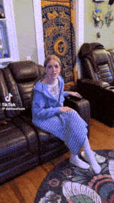a tiktok video of a woman sitting on a couch with a zodiac sign tapestry in the background