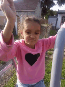 a little girl in a pink shirt with a black heart on it