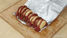 a piece of meat is wrapped in tin foil on a wooden cutting board that says made in animatica