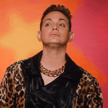 a man wearing a leopard print jacket and chain around his neck