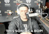 a man wearing headphones says this song is a bop in front of a microphone