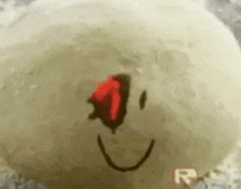 a close up of a smiley face with a red eye on a white surface .