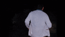 a man in a white coat is walking through the dark