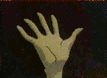 a white hand is reaching up in front of a red curtain .