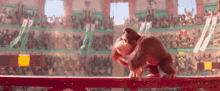 a monkey is walking on a red railing in front of a crowd in a stadium .
