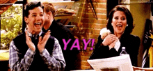 a man and a woman are clapping and laughing while sitting at a table .