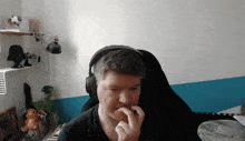 a man wearing headphones is sitting in a chair and biting his nails