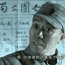 a man wearing a hat is standing in front of a piece of paper with chinese writing on it