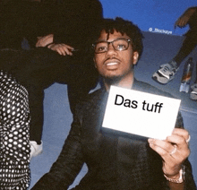 a man holds up a card that says das tuff