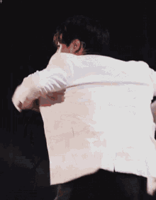 a man in a white suit is dancing on a stage
