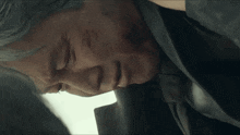 a man in a suit and tie is laying down with blood on his face and neck .