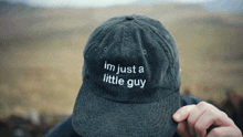 a person wearing a hat that says ' im just a little guy ' on it