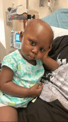 a little girl is sitting on a person 's lap in a hospital bed .