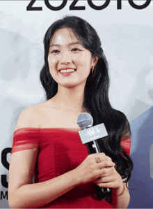 a woman in a red dress smiles while holding a microphone with a sign that says awa on it