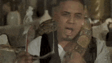 a man with a snake around his neck holds a fork in his mouth