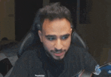 a man is sitting in a chair with his hand on his face .