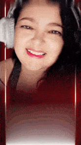 a woman wearing headphones is smiling with a red background behind her