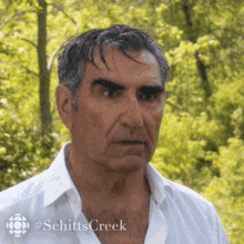 a man in a white shirt with #schitts creek on the bottom right