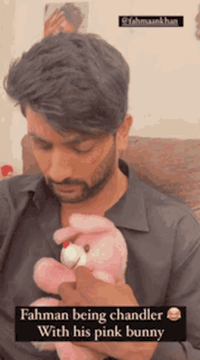 a man is holding a pink stuffed bunny and the caption says ' rahman being chandler with his pink bunny '