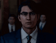 a man wearing glasses and a suit is looking at the camera