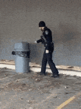 a police officer is walking towards a garbage can in a parking lot