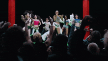 a group of women are dancing on a green background