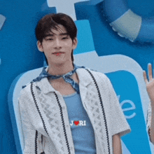 a man wearing a blue tank top and a white shirt is standing in front of a blue bottle .