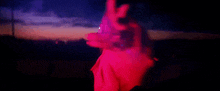 a man in a red jacket is looking out a window at a sunset
