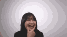 a young woman is laughing and touching her face with her finger .