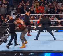 a man in a suit stands in the middle of a wrestling ring with a crowd watching