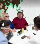 a group of people are sitting around a table with tiktok written on the bottom right corner