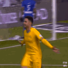 a man in a yellow jersey is running on a soccer field in front of a sign that says ittvv gifs