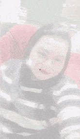 a woman in a black and white striped shirt is taking a selfie with her eyes closed .